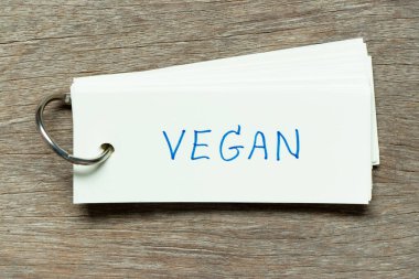 Tahta arka planda el yazısı vegan olan flaş kart.