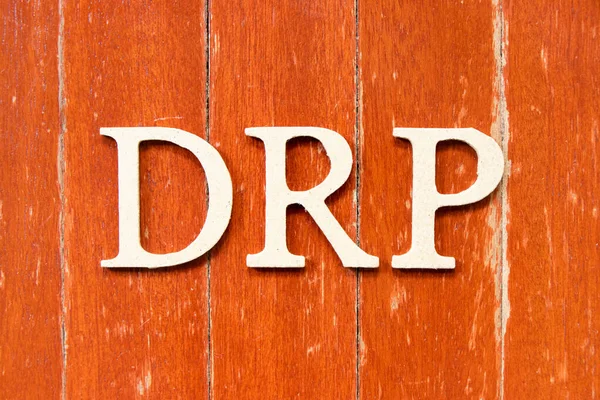 Alphabet letter in word DRP (Abbreviation of Disaster recovery plan, Distribution resource planning, Dividend reinvestment plan, Direct Repair Program or Digital Remaster Processing) on old red color wood plate background