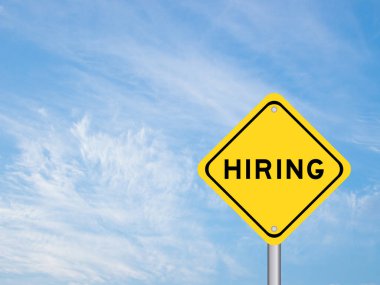 Yellow transportation sign with word hiring on blue color sky background
