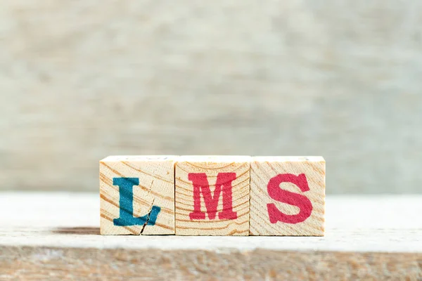 Alphabet letter block in word LMS (Abbreviation of Learning management system) on wood background