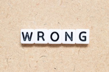 Tahta zemin üzerinde yanlış sözcük içeren beyaz kiremit alfabesi harfi