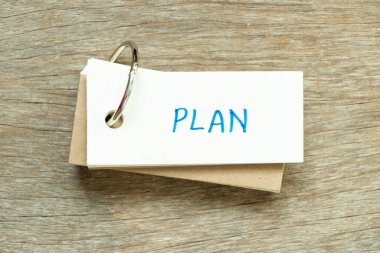 Flash card with handwriting word plan on wood background