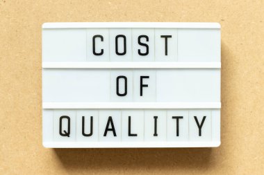 Ahşap arka planda kelime kalitesi maliyetli ışıkkutusu