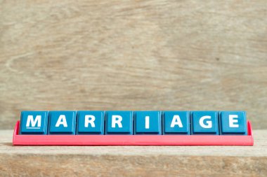 Tile alphabet letter with word marriage in red color rack on wood background