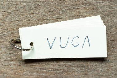 VUCA (kararsızlığın, belirsizliğin, karmaşıklığın ve belirsizliğin kısaltması) sözcüğünün el yazısı olan flaş kart ahşap arka planda