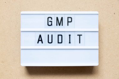 Lightbox with word GMP (Good manufacturing practice) audit on wood background