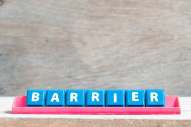 Tile alphabet letter with word barrier in red color rack on wood background
