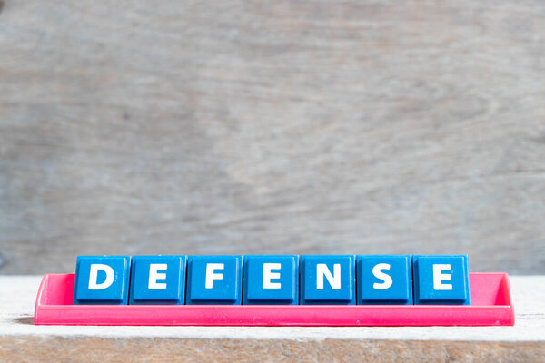 Tile alphabet letter with word defense in red color rack on wood background
