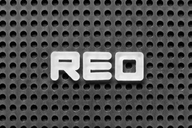 White alphabet letter in word REO (Abbreviation of Real estate owned) on black pegboard background