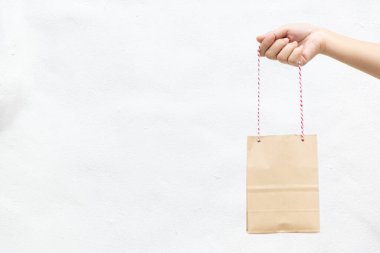 Hand of business woman hold brown paper shopping bag on white concrete background