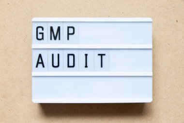 Lightbox with word GMP (Good manufacturing practice) audit on wood background