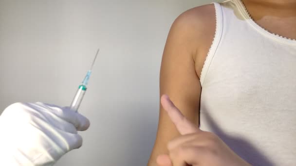 注射器のワクチンで医者の手は子供の手でワクチンを接種したい 子供は恐れていると彼は注射を望んでいないことを彼の手で示しています — ストック動画