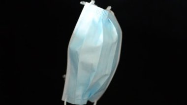 Noel çelenginde koruyucu bir tıbbi maske renkli ışıklarla parlar ve parlar.