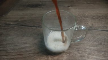 Barmen şeffaf bir bardakta süte kahve doldurur.