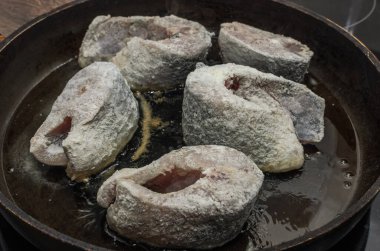 Aşçı kızartma tavasında sazan balığı kızartır.