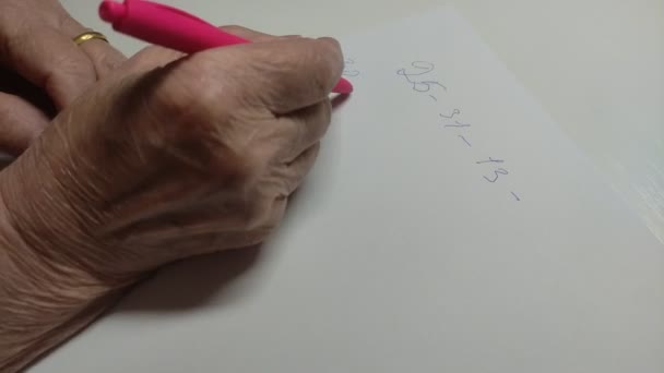 Yaşlı Bir Kadının Eli Bir Kağıt Parçasına Kalemle Rakamlar Yazar — Stok video