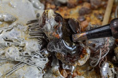 Usta lehimleme demiriyle tenekeyi eritiyor.