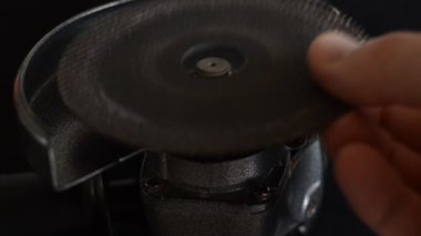 The master installs the cutting wheel in the angle grinder