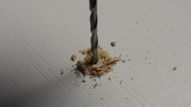 The master drills a hole in a wooden plank with a drill