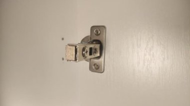 Mobilyacı dolaba mobilya menteşeleri yerleştiriyor, vidayı tornavidayla sıkıyor.