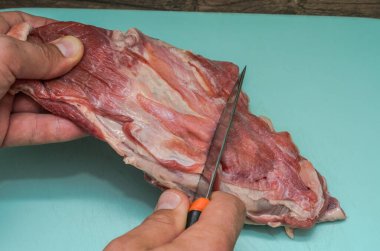 Kasap kesme tahtasındaki bıçakla kuzu eti keser.