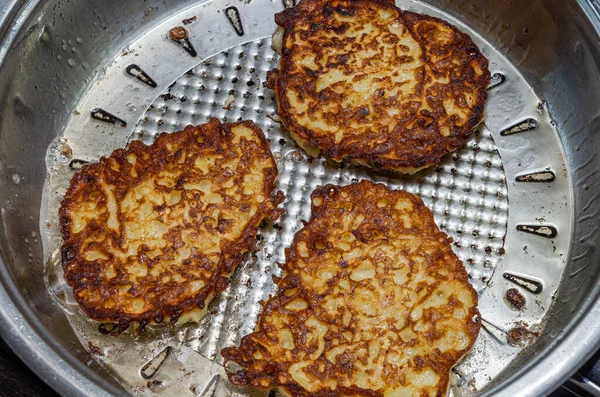 The cook fries zucchini pancakes in a pan