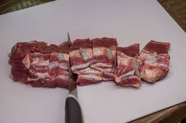 Butcher cuts lamb fillet with a knife on a cutting board