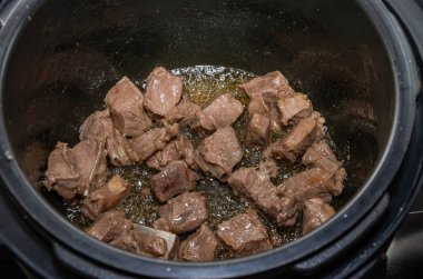The cook fries pieces of lamb meat in a pan