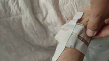 The doctor makes a dressing of the wound on the arm of an elderly patient, removes the adhesive plaster with a bandage