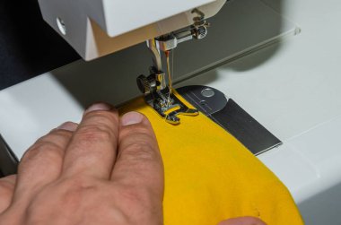 Tailor sews fabric for clothing on a sewing machine in a tailor shop