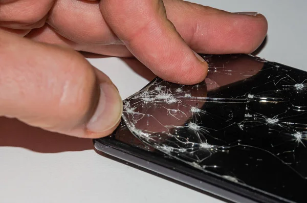 The master in the service center changes the broken glass of the screen in the smartphone