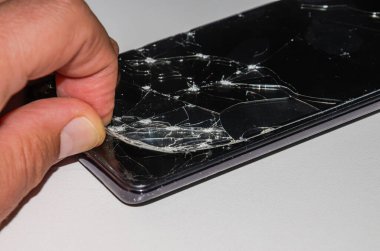 Servis merkezindeki usta akıllı telefondaki kırık camları değiştiriyor.