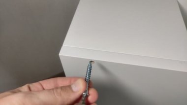 Mobilya montajcısı mobilya tahtalarının parçalarını bir doğrulama ve bir elektrikli tornavida ile birbirine bağlar