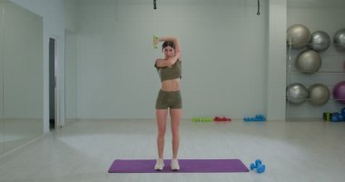 Sporty girl performs french press from behind head