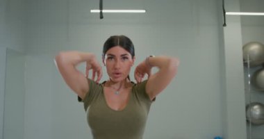 Brunette girl kneads shoulder joints and muscles, rotates her arms
