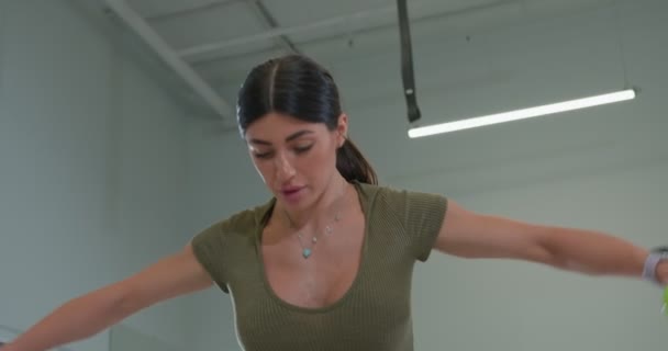 Athletic physique brunette girl performs an exercise of raising dumbbells — Stockvideo