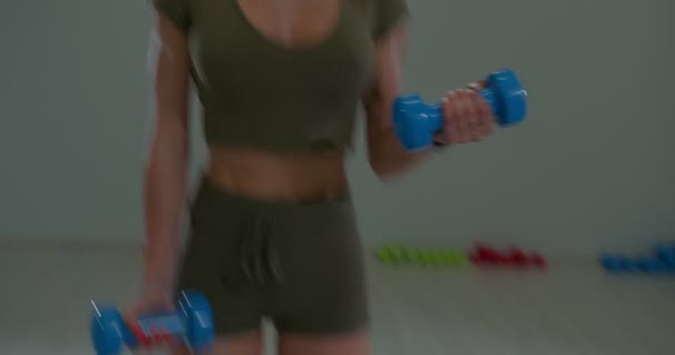 Athletic shape brunette girl performs flexion of arms for biceps alternately — Vídeo de Stock