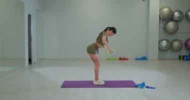 Spor kızı halterleri yana doğru sallıyor.