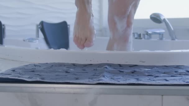 Los pies de hombre salen del jacuzzi con espuma en la alfombra — Vídeos de Stock