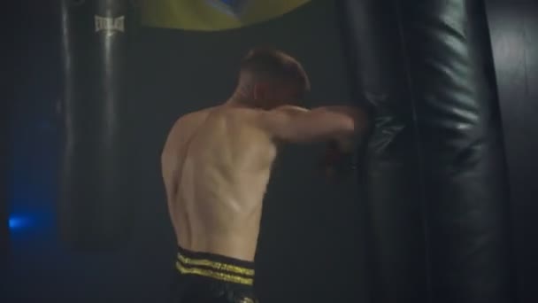 Boxer udělá sérii úderů na boxovací pytel pomocí paží a nohou — Stock video