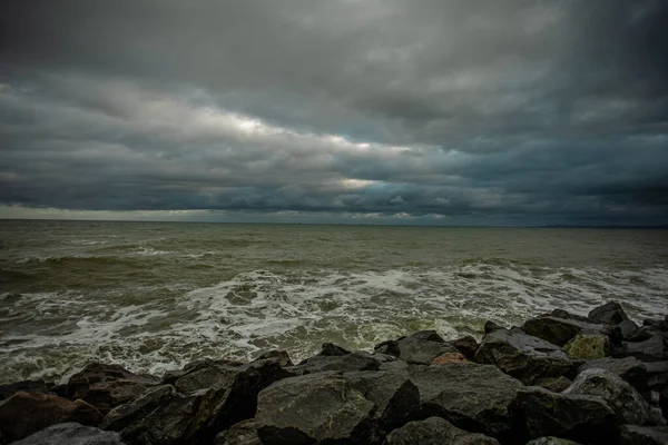 Drammatico cielo sul mare nero con onde, nuvole e pietre — Foto Stock