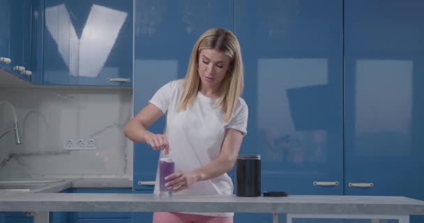 Fit girl agita bsaa de color púrpura en vaso de agua — Vídeos de Stock