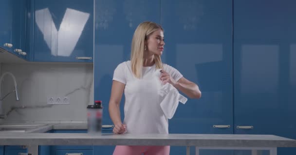 Красивая блондинка выбрасывает белую футболку из кадра — стоковое видео
