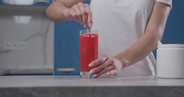 Frauenhand rührt Bcaa im Glas um, Wasser wird rot — Stockvideo