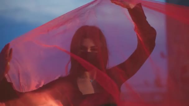 Girl in mask moves under a red transparent cloth — Stock Video