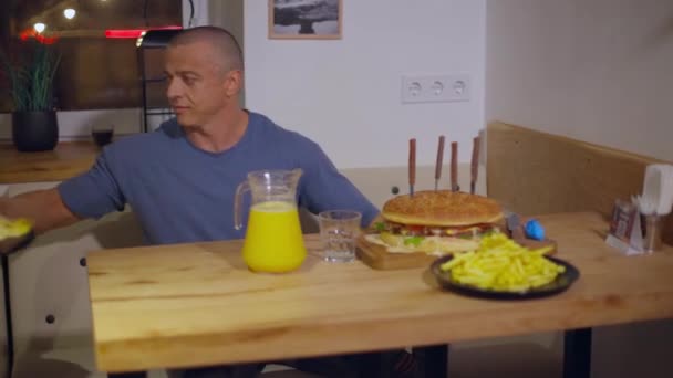 Muž sedí u stolu, mění talíře a připravuje se na jídlo. — Stock video