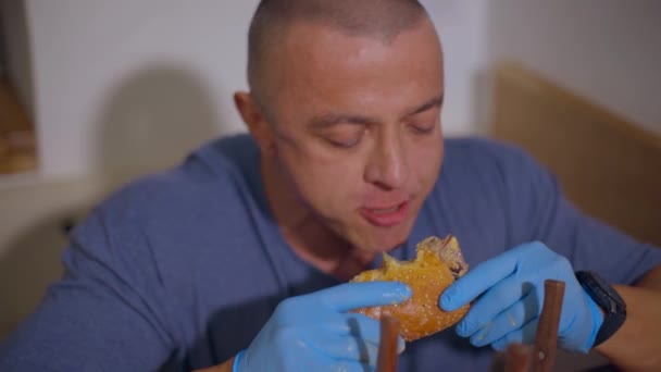 Az ember étvágygerjesztően szaftos hamburgert eszik. — Stock videók