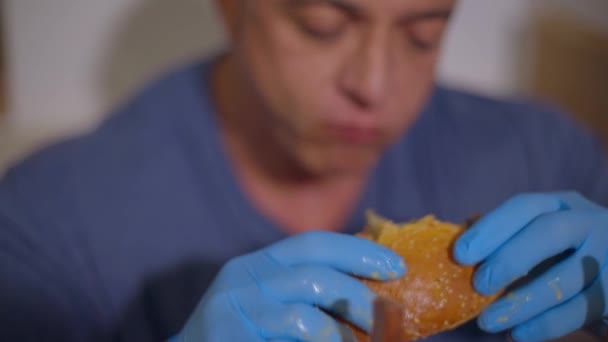 Burger in Männerhand im Vordergrund — Stockvideo