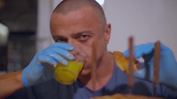 Vuxen man äter saftig burgare och dricker apelsinjuice — Stockvideo