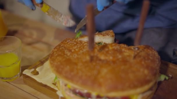 Tek kullanımlık eldivenli bir erkek eli sulu bir burgeri keser. — Stok video